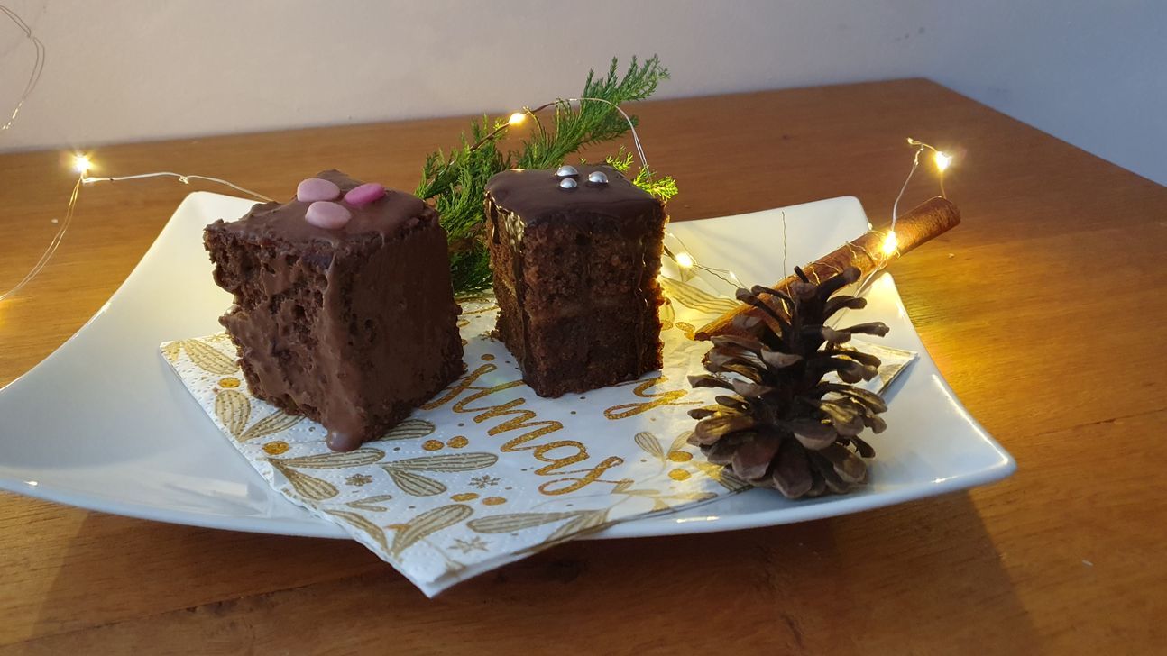 Kleine Kuchen, die mit Schokolade überzogen sind, auf einem weißen, eckigen Teller.